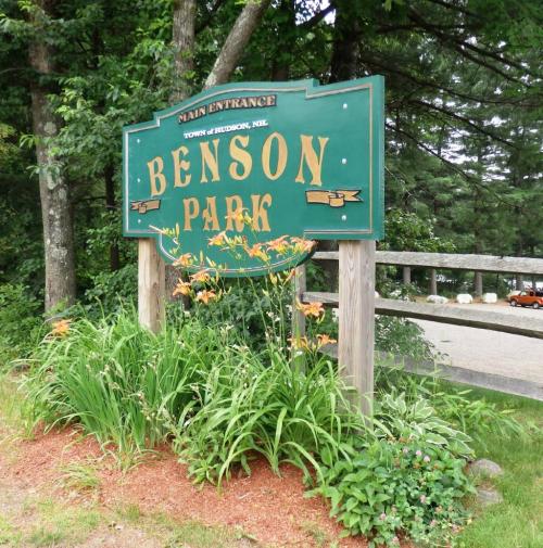 Sign for Benson Park at the main entrance, surrounded by greenery and flowers.