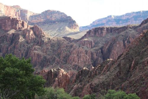 Rocky mountain landscape with steep cliffs and greenery in the foreground, showcasing rugged terrain and natural beauty.