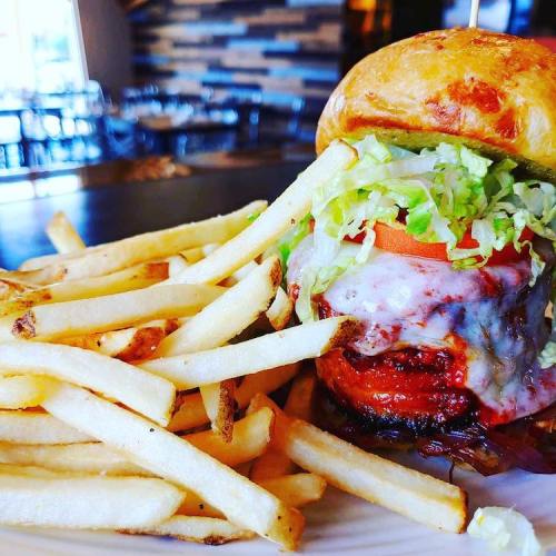 A juicy burger with lettuce, tomato, and melted cheese, served with a side of golden French fries.