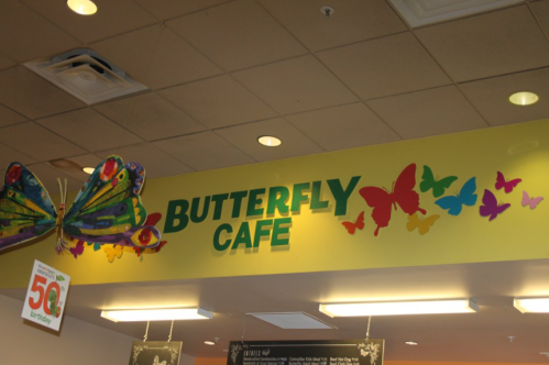 Colorful sign for "Butterfly Cafe" with butterflies and a large butterfly decoration above.