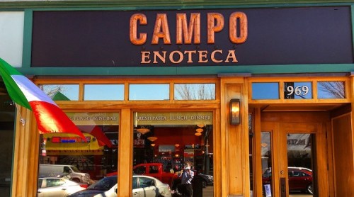 Exterior of Campo Enoteca restaurant, featuring a wooden sign and an Italian flag.