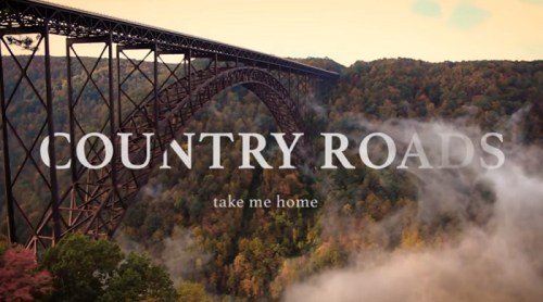 A scenic view of a bridge over a forested landscape with the text "Country Roads take me home" overlaying the image.