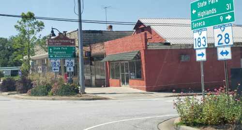 A street view showing directional signs for State Park, Highlands, and Westminster, with a red brick building in the background.