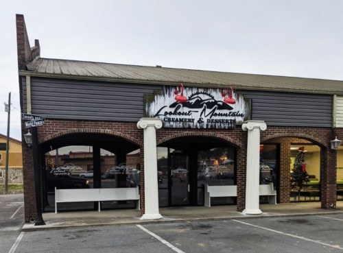 Exterior of a shop named "Coconut Mountain Creamery & Preserves," featuring a sign and large windows.