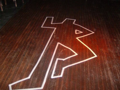 A wooden floor with a white outline of a running figure, illuminated by a warm light.