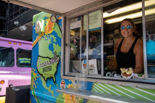 A smiling woman serves food from a colorful food truck window, showcasing a vibrant map design.