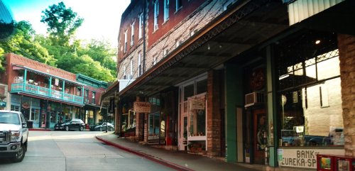 A charming street scene in Eureka Springs, featuring historic buildings, shops, and a winding road.