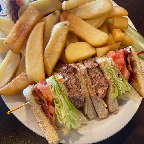 A plate featuring a sliced sandwich with lettuce, tomato, and bacon, accompanied by golden, crispy fries.