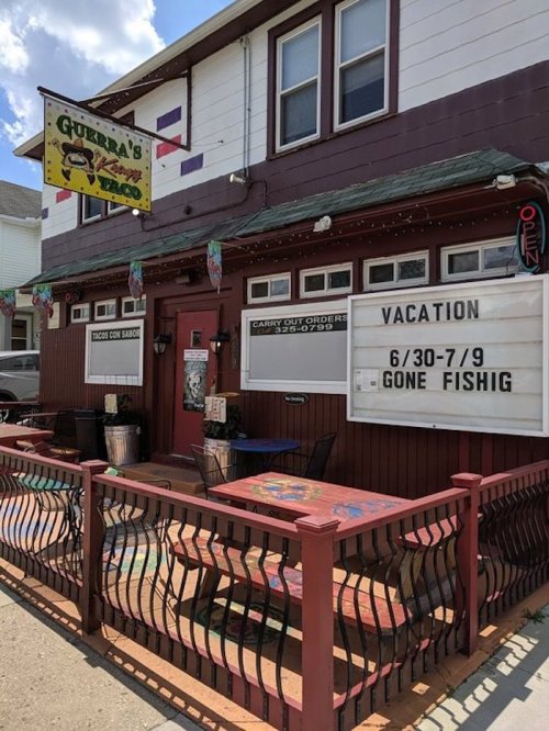 A colorful restaurant exterior with a sign announcing vacation dates and a "Gone Fishin'" message.