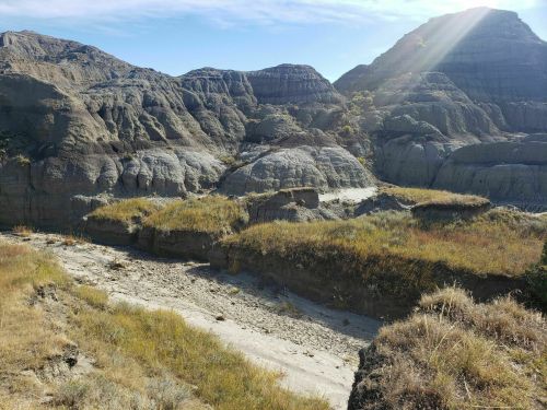 A rugged landscape featuring gray rock formations and sparse vegetation under a clear blue sky.