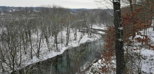 A serene winter landscape featuring a river surrounded by snow-covered trees and a tranquil, icy atmosphere.