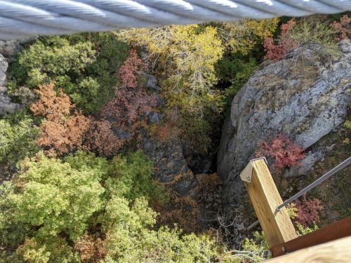 Aerial view of a rocky gorge surrounded by colorful autumn foliage in vibrant shades of orange, yellow, and green.
