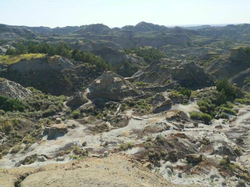 A vast landscape of rugged hills and valleys, featuring rocky formations and sparse vegetation under a clear sky.