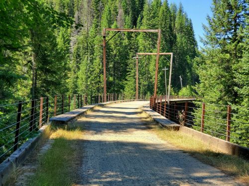 A gravel path leads through a forest, with old metal structures and power lines visible on either side.
