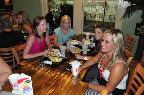 A group of four women enjoying a meal together at a restaurant, laughing and chatting at a wooden table.