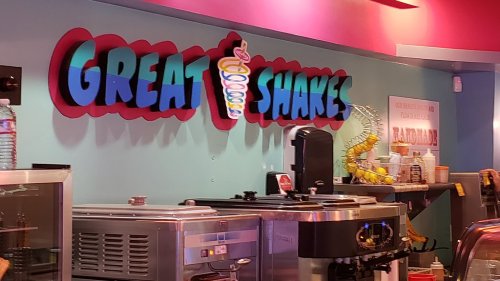 Colorful sign reading "Great Shakes" above a counter with ice cream machines and a vibrant, playful decor.