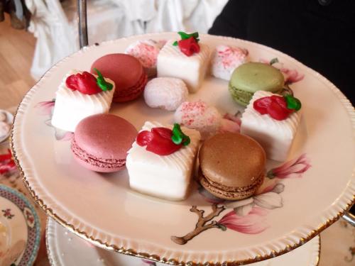 A decorative plate with colorful macarons and small cakes topped with frosting and decorations.