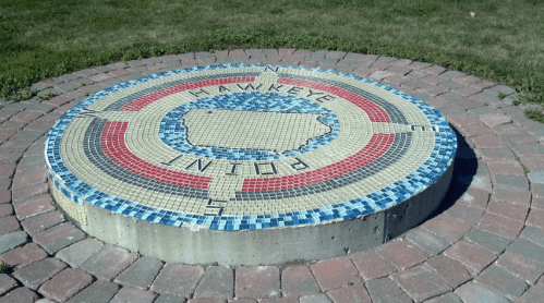 Mosaic compass design featuring the outline of Iowa, labeled "Hawkeye Point," surrounded by a circular stone path.