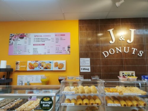 Menu board and display case at J&J Donuts, featuring various pastries and a special combo offer.