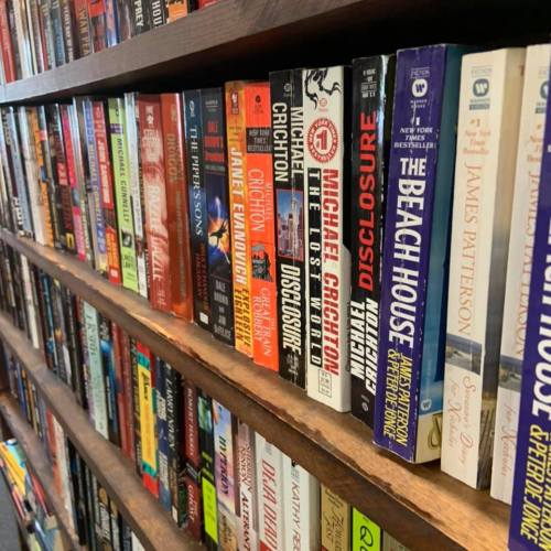 A close-up of a bookshelf filled with various books, showcasing colorful spines and titles by different authors.