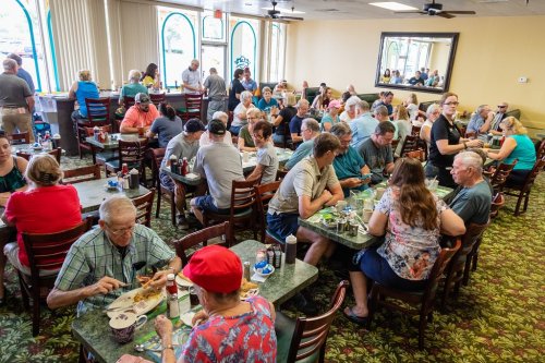 A busy restaurant filled with diners at tables, enjoying meals and chatting in a lively atmosphere.