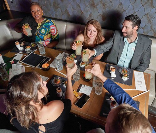 A group of friends toasting with cocktails at a restaurant, enjoying a lively dining experience together.