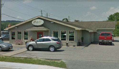 A restaurant building with a sign reading "M & B's," featuring parked cars and a clear blue sky.