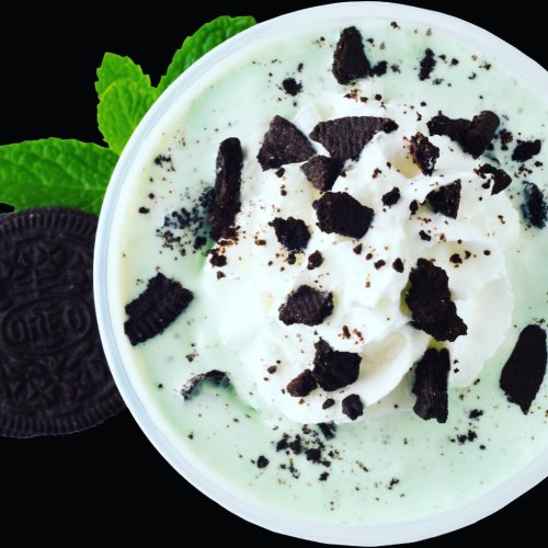A creamy mint dessert topped with whipped cream and crushed Oreo cookies, garnished with fresh mint leaves.