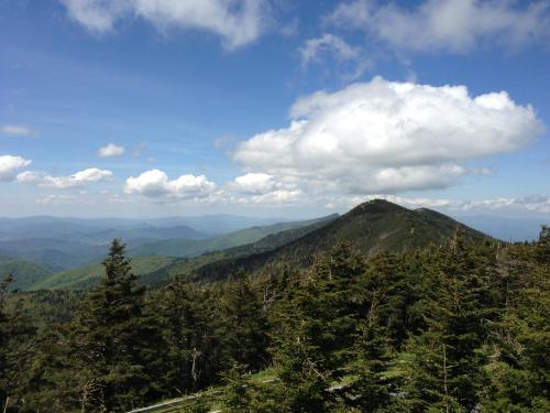 A scenic view of green mountains under a blue sky with fluffy clouds, showcasing a peaceful natural landscape.