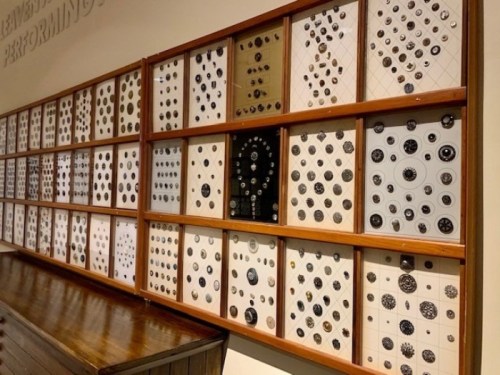 A wall display featuring various circular objects arranged in a grid pattern, showcasing intricate designs and textures.