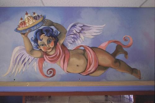 A whimsical mural of a cherubic figure with blue hair, flying and holding a plate of ice cream sundaes.