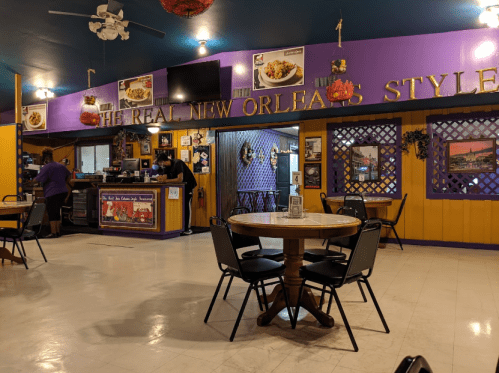 Interior of a colorful restaurant with purple walls, tables, and a counter, featuring New Orleans-style decor.