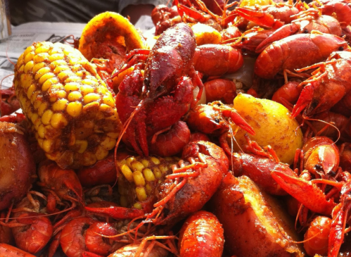 A close-up of a pile of crawfish, corn, and potatoes, seasoned and ready to eat.