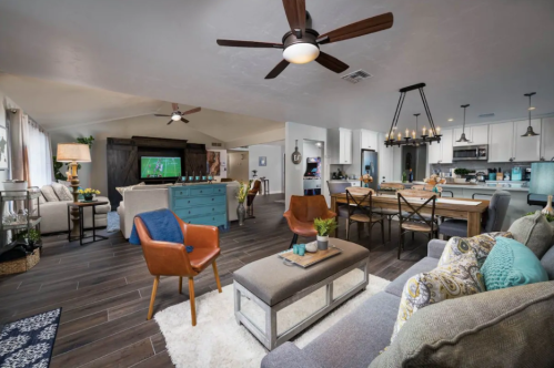 A modern living room and dining area with a cozy sofa, wooden dining table, and a TV in a bright, open space.