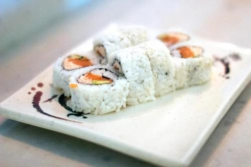 A plate of sushi rolls with rice, fish, and vegetables, arranged neatly on a decorative dish.