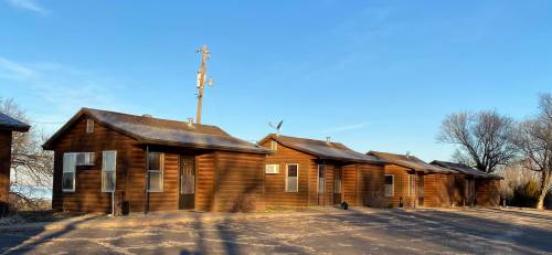 Row of rustic wooden cabins under a clear blue sky, with a power pole in the background.