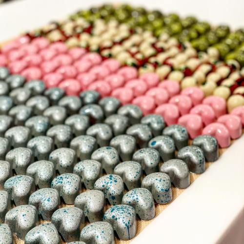 A colorful array of decorative candies arranged in rows, featuring various shades of pink, green, and blue.