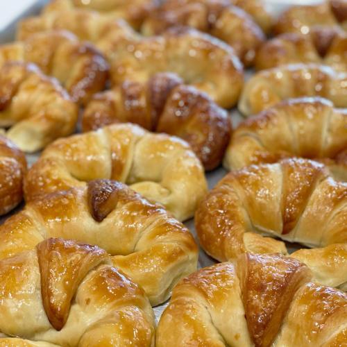 A close-up of freshly baked golden-brown croissants arranged on a tray.
