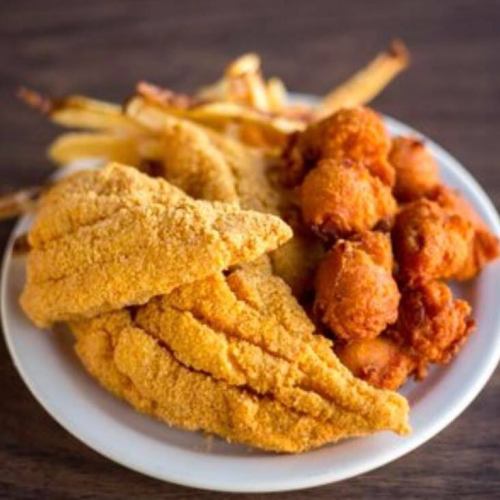 A plate of fried fish fillets, hushpuppies, and French fries.
