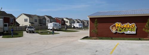 View of Monkey Island RV Resort with parked RVs and colorful cabins under a clear blue sky.