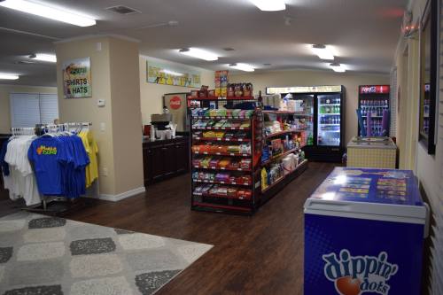 Interior of a store featuring snacks, drinks, and merchandise like shirts and hats, with a Dippin' Dots freezer.