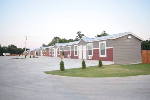 Row of modern, single-story buildings with a paved driveway and small shrubs in a quiet setting.
