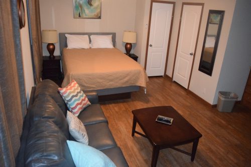 Cozy bedroom with a bed, nightstands, a sofa, coffee table, and artwork on the walls. Warm, inviting atmosphere.