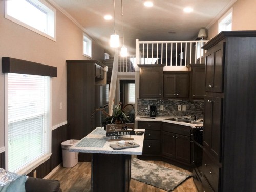 Cozy interior of a small home featuring a kitchen, living area, and loft space with natural light and modern decor.