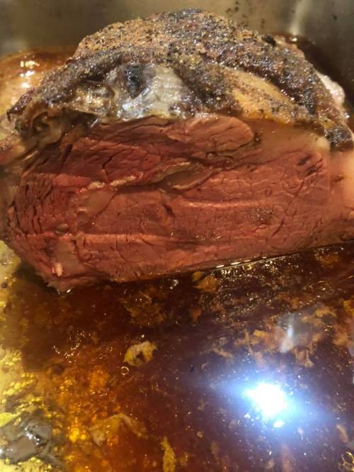 A close-up of a perfectly cooked roast beef resting in a savory brown sauce.