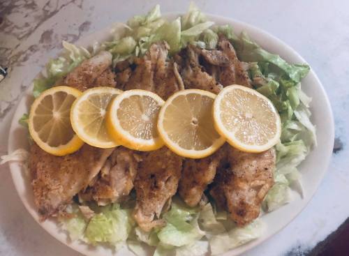 A platter of fried fish fillets garnished with lettuce and lemon slices.