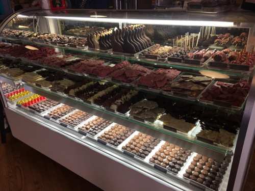 A display case filled with a variety of chocolates and confections, including bars, truffles, and coated treats.
