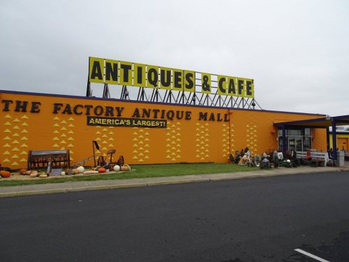 Bright yellow building with "Antiques & Cafe" sign, featuring pumpkins and decorations outside the Factory Antique Mall.