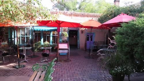 A charming outdoor café with colorful umbrellas, brick pathways, and lush greenery.