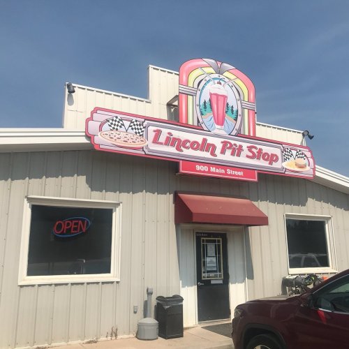 A building with a colorful sign reading "Lincoln Pit Stop" and an "Open" sign in the window.